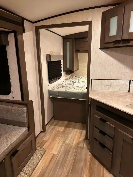 Spacious RV rental interior with a cozy bed bunk, comfortable dinette seating, and a functional kitchen counter. Perfect for road trips.. Cruiser RV MPG Ultra Lite 2022