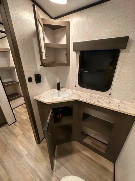 Inside an **RV rental**: a modern bathroom vanity with a sink, black faucet, marble-look counter, and storage. Bright, clean space.. Cruiser RV MPG Ultra Lite 2022
