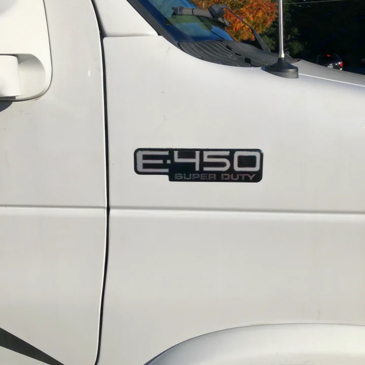 White Ford E-450 Super Duty van's side, showing the E-450 badge; a common vehicle type for an rv rental.. Forest River LEXINGTON 235 2006