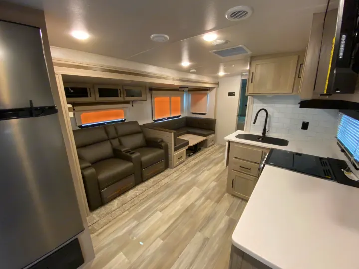 Modern RV rental interior showcasing a comfortable living area with recliners & dinette, plus a functional kitchen.. Forest River Rockwood 2023