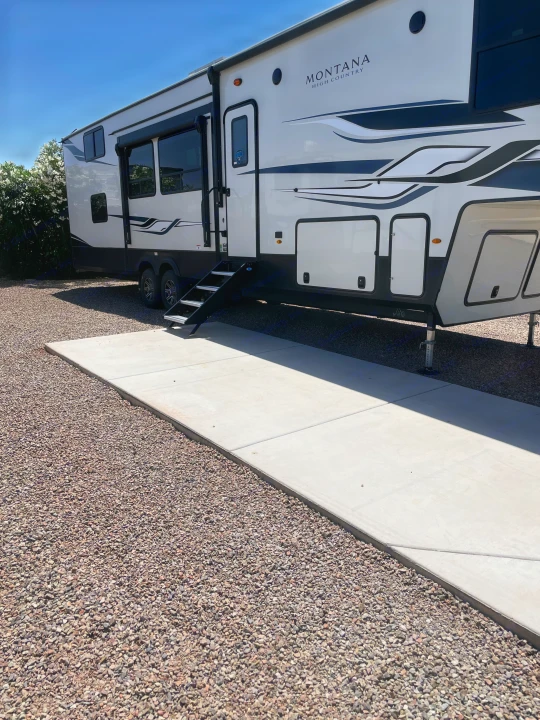 Spacious fifth-wheel RV rental on a sunny gravel site with concrete pad. Ideal for travel & leisure.. Keystone RV Montana High Country 2023