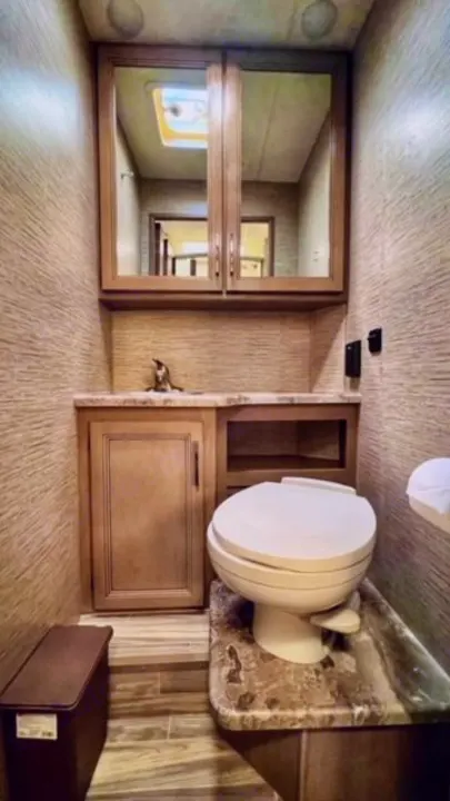 Well-appointed RV rental bathroom featuring a modern toilet, sink, and mirrored cabinet for comfort on the road.. Thor Four Winds 2022