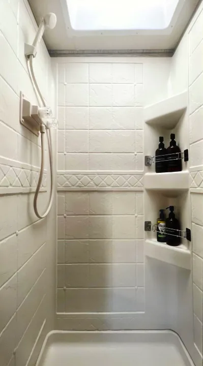 Clean RV rental shower: handheld shower, skylight, and shelves stocked with toiletries. Compact for easy travel.. Thor Four Winds 2022