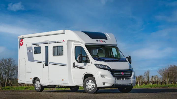 White Pilote motorhome, an ideal RV rental. Parked outdoors under a bright blue sky.. Pilote P696S 2025