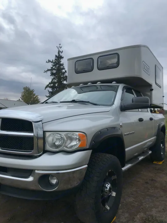 Silver Ram pickup with a grey Scout truck camper, ideal for your next RV rental adventure.. Dodge Dodge Bighorn 3500 Heavy Duty Pu 2005