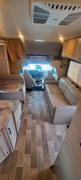 Spacious RV rental interior featuring a dinette, sofa, and cockpit view. Perfect for comfortable travel adventures.. Thor Chateau 2021