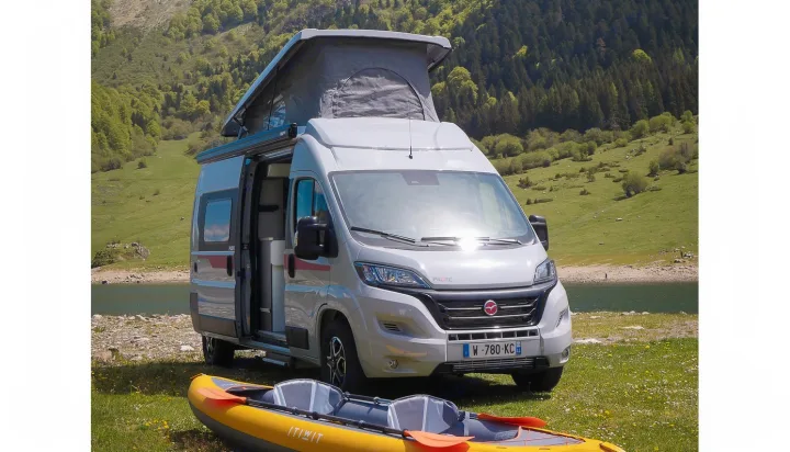 An RV rental adventure! A grey camper van with pop-top roof by a lake, with a kayak in the foreground for outdoor travel.. Pilote V600 Toit relevable 2024