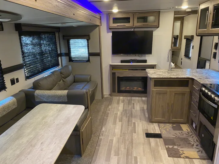 Modern RV rental interior with dining, kitchen, and living areas. Features TV, fireplace, and comfy sofa.. Keystone Crossroads Zinger 2021