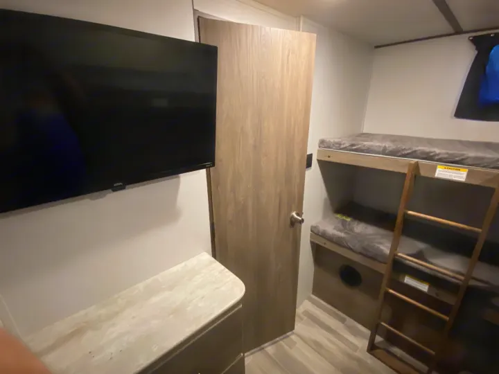 This RV rental offers cozy bunk beds and a TV, showcasing a modern interior design for comfortable travel.. Keystone Crossroads Zinger 2021