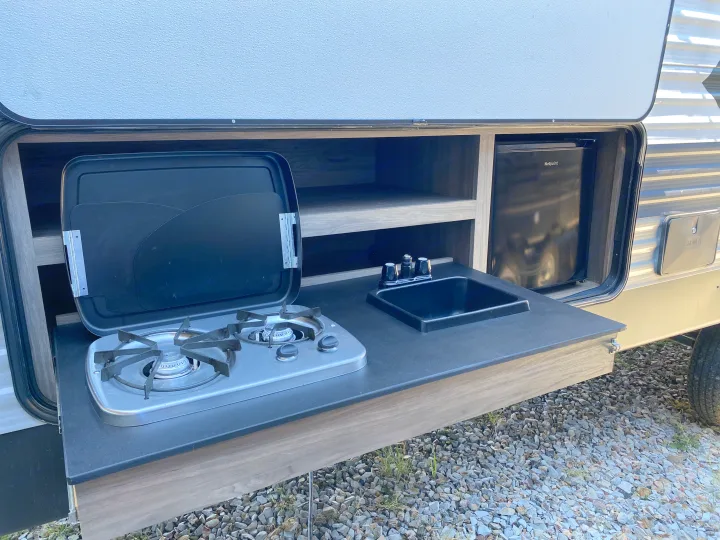 This RV rental features a convenient outdoor kitchen with a stove, sink, and mini-fridge for easy camping.. Keystone Crossroads Zinger 2021