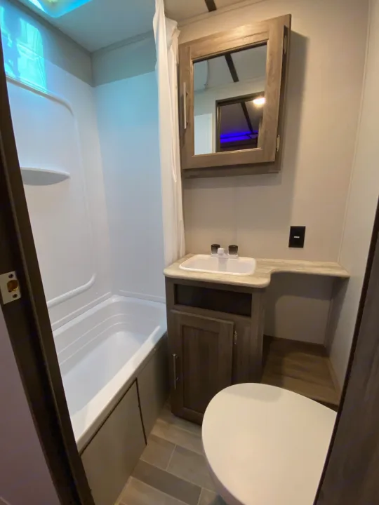 Compact RV rental bathroom featuring a tub, sink, and toilet.. Keystone Crossroads Zinger 2021