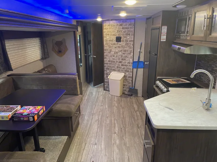 Cozy RV rental interior showcasing a dining area with puzzles, kitchen, and modern amenities.. Forest River Cherokee Grey Wolf 2019
