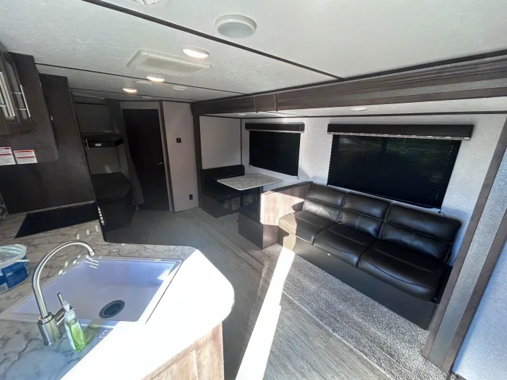 This clean RV rental showcases a bright interior with a kitchen, dinette, and sofa. Modern and ready for adventure.. Aspen Trail Aspen Trail Trailer 2021