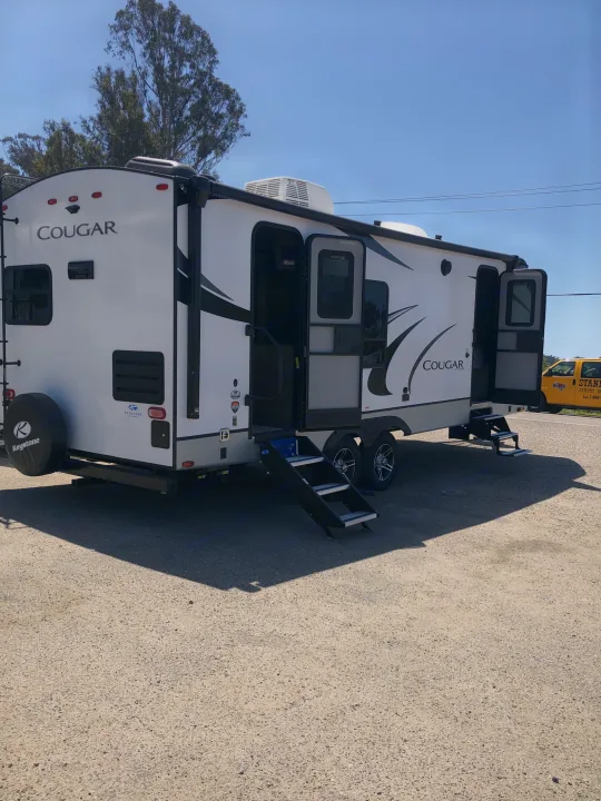 White Cougar travel trailer ready for your next adventure. Explore this spacious RV rental with easy-access steps.. Keystone RV Cougar 2021