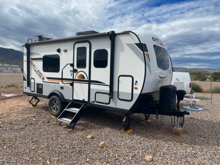 White & gray GEO PRO travel trailer, an ideal RV rental for your next camping adventure. Parked on a gravel lot under cloudy skies.. Forest River Geo Pro 2021