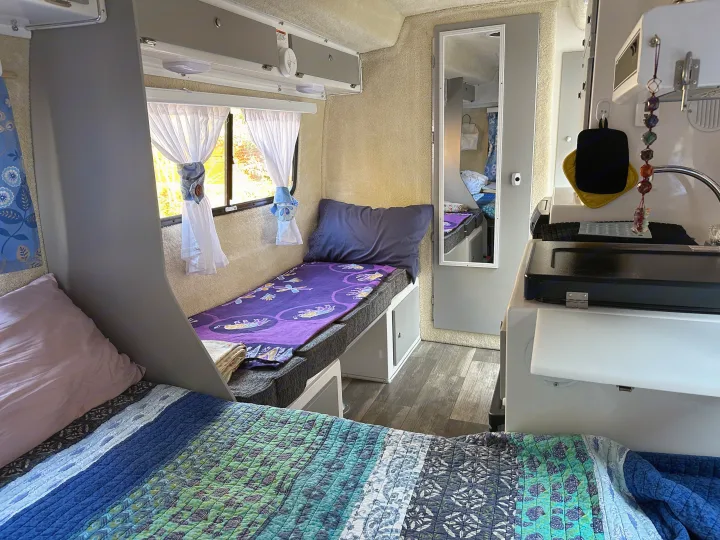 Cozy RV rental interior with a bunk bed, main bed, and compact kitchen, offering a functional and comfortable mobile living space.. Casita Spirit 2023