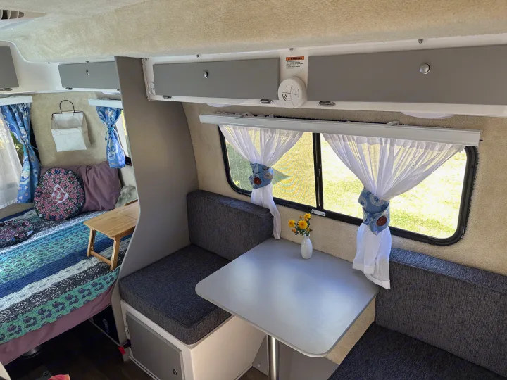 Cozy RV rental interior showing a dinette, sleeping area, and overhead storage for your next adventure.. Casita Spirit 2023