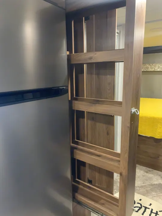 RV rental interior shows sleek refrigerator and pull-out pantry next to a bright bedroom.. Forester Classic 2021