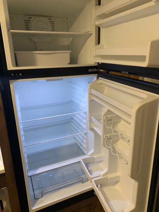 An open, empty RV rental refrigerator, featuring clean shelves and door compartments.. Forester Classic 2021