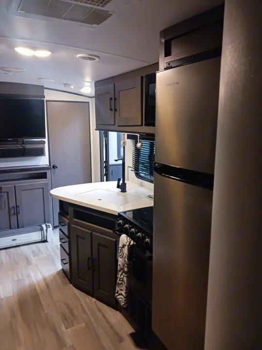 Spacious RV rental interior with a modern kitchen, stainless steel refrigerator, and entertainment area.. Embrace EL310 2021
