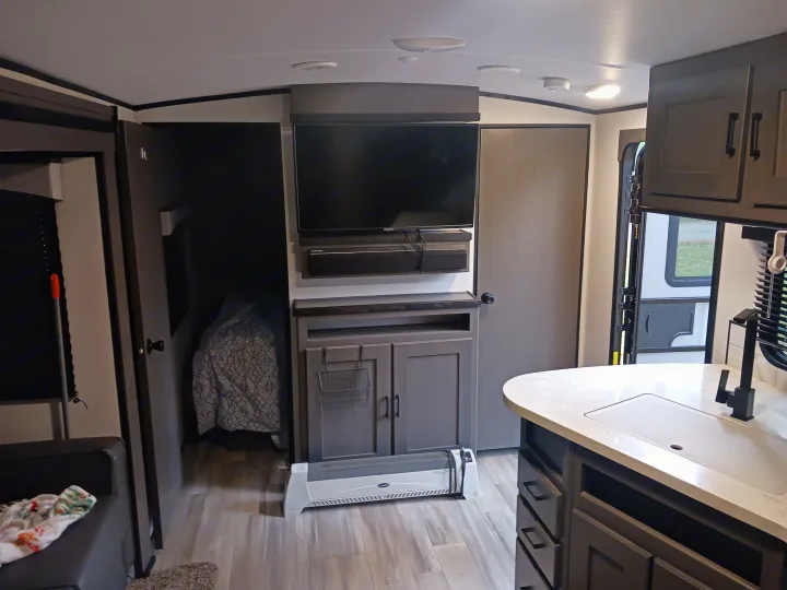 Modern RV rental interior: living area with TV, kitchen, and partial bedroom view visible.. Embrace EL310 2021