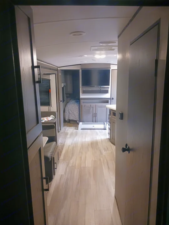 View down the aisle of an RV rental showing the living area, kitchen, and bedroom beyond.. Embrace EL310 2021