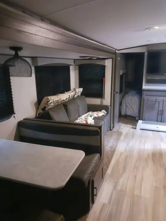 RV rental living space with dining booth, couch, TV, and bunk area for a cozy stay.. Embrace EL310 2021