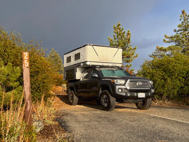 Dark gray Tacoma truck with a pop-up overland camper, ideal for an RV rental or camping trip at site 25.. Four Wheel Campers Fleet 2021