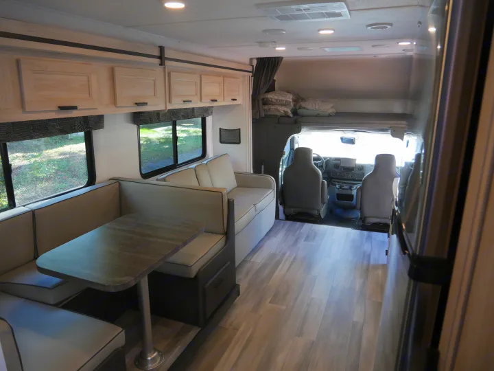 Spacious RV rental interior with dinette, sofa, and bunk overhead, perfect for family adventures on the road.. Forest River Sunseeker Classic 2023