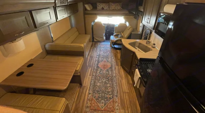 Spacious RV rental interior featuring a full kitchen, dining area, sofa, and an overhead bed for comfortable travel.. Nexus 35TSC 2020