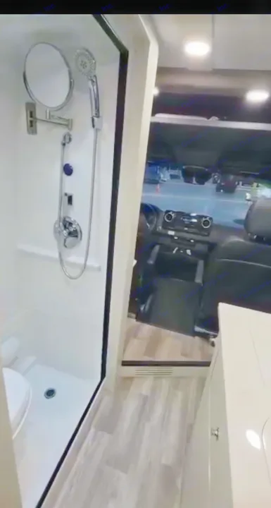RV rental interior: a compact shower/toilet with mirror, wood-look flooring, and the vehicle's front dashboard.. Cahaba Cahaba Class B 2022