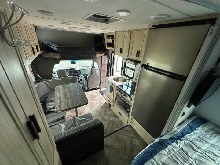 Spacious RV rental interior featuring a full kitchen, dining area, bed, and driver's cab, ideal for road trips.. Forest River Sunseeker 2022
