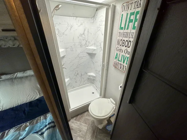Inside this RV rental, featuring a compact bathroom with a shower and toilet, plus a peek at the cozy bedroom.. Forest River Sunseeker 2022