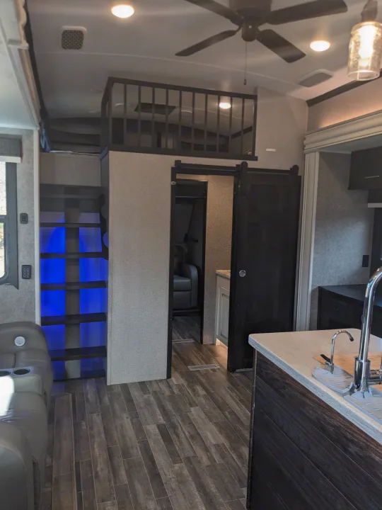 Modern RV rental interior: living space with kitchen, loft, and blue LED stairs.. Jayco North Point 2021