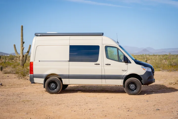 Tan camper van RV rental in a desert landscape with saguaro cacti and mountains under a clear blue sky.. VanCraft VanCraft Class B 2022