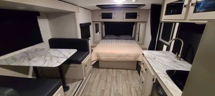 Spacious RV rental interior with modern bedroom, dining area, and compact kitchen featuring a sleek sink and counters.. Forest River inc Apex 208 BHS 2024