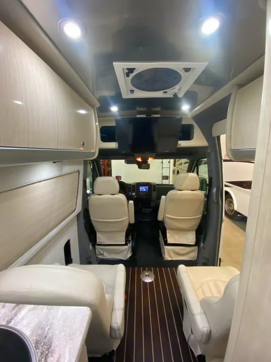 Step inside this modern rv rental: a luxurious RV interior with white leather captain's chairs, overhead TV, and wood floor.. Airstream Interstate 2017