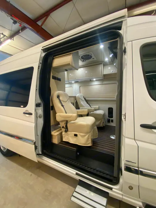 Open door of a white luxury RV rental, showcasing its premium interior with cream captain's chairs and custom finishes.. Airstream Interstate 2017