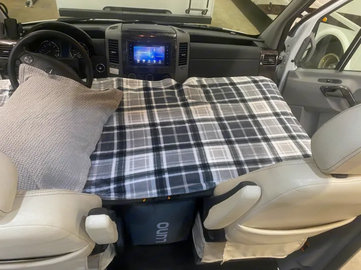 Inside an RV rental: front cabin converted to a bed with a plaid blanket & Luno air mattress for overnight stays.. Airstream Interstate 2017