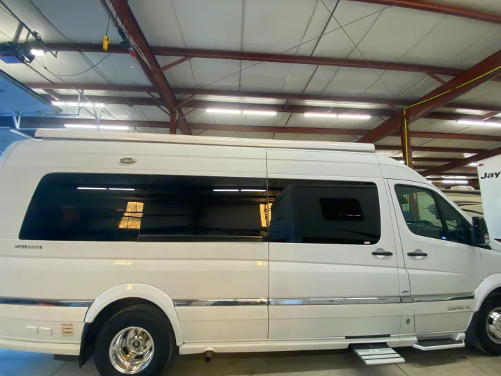 Side view of a white Airstream Interstate RV, featuring large tinted windows and chrome trim. A perfect choice for an rv rental.. Airstream Interstate 2017