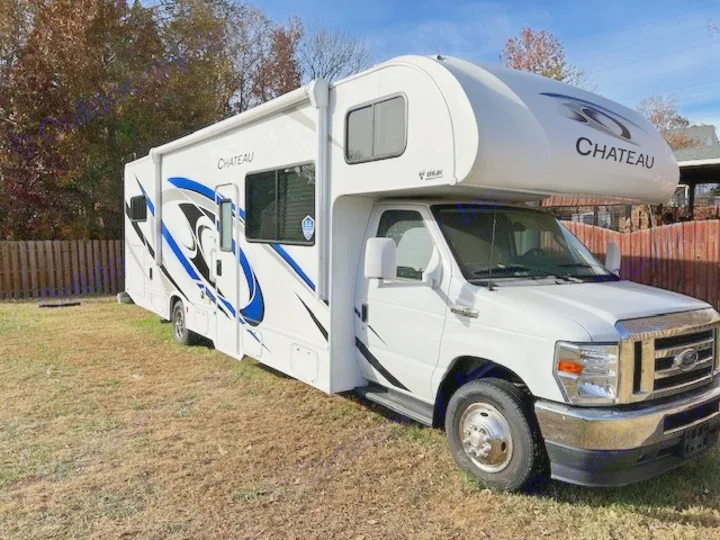 This white Chateau Class C RV rental is perfect for outdoor travel, parked on a grassy lawn under a clear sky.. Thor Chateau Victory 2022