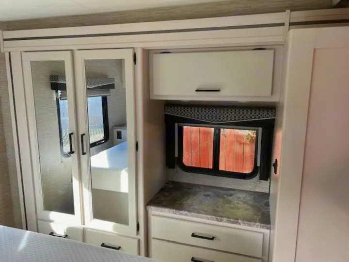 RV rental interior: Mirrored closet, cabinet, window & storage unit. Bright, modern bedroom setup.. Thor Chateau Victory 2022