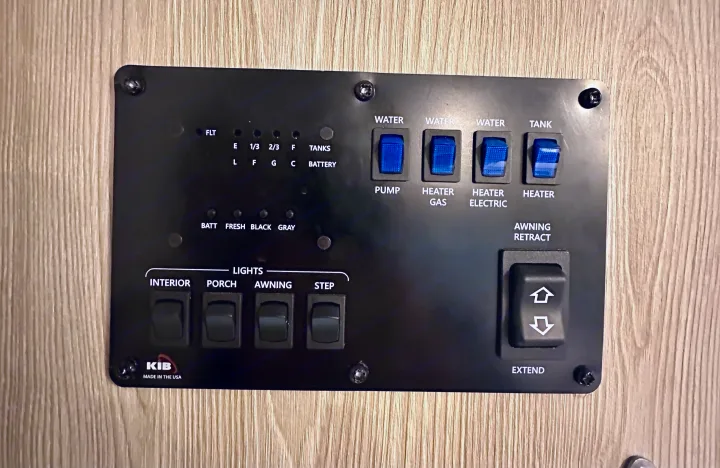 This RV rental control panel shows switches for water pump, heaters, lights, and awning, plus tank and battery level indicators.. Forest River Geo Pro 2021