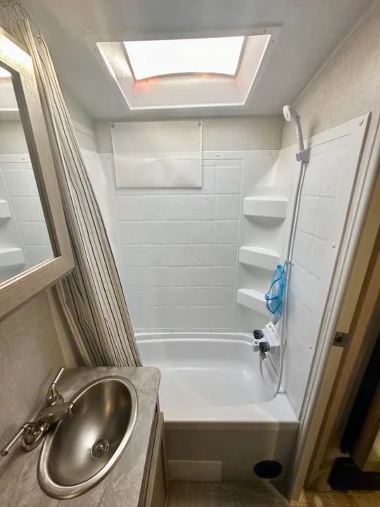 Clean RV rental bathroom featuring a shower/tub, modern sink, and overhead skylight for natural light.. Forest River Geo Pro 2021