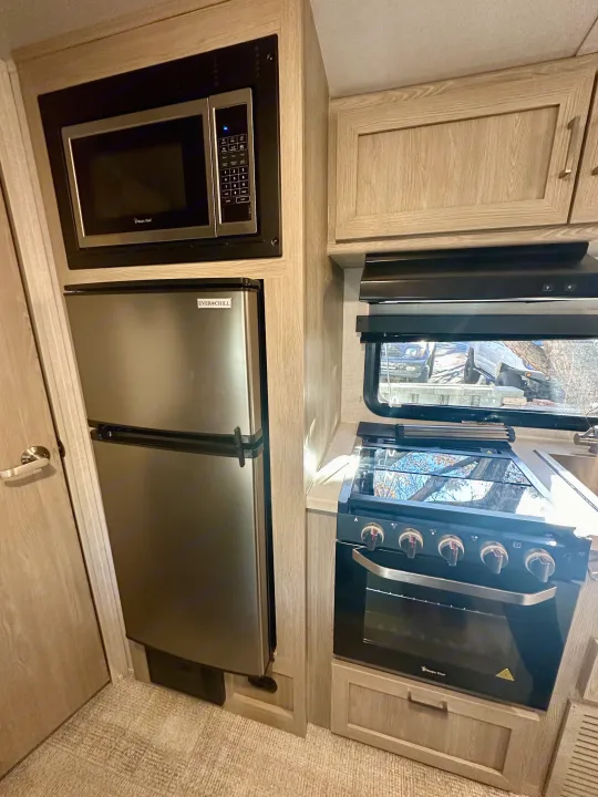 RV rental kitchen: stainless steel fridge, Magic Chef microwave, and stove/oven. Compact and fully equipped for your adventures.. Forest River Geo Pro 2021