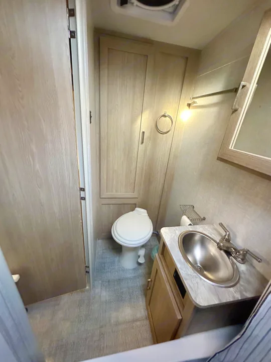 Compact RV rental bathroom featuring a white toilet, sink vanity, and built-in storage. Practical for travel accommodation.. Forest River Geo Pro 2021