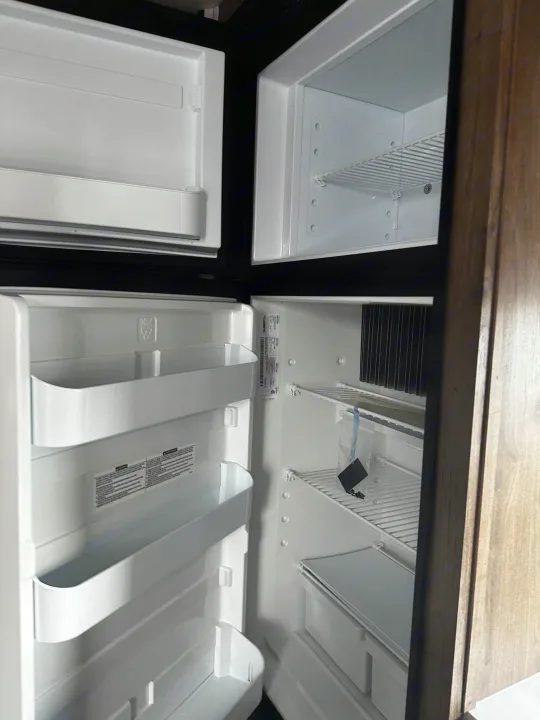 New, empty refrigerator and freezer within an RV rental, ready for your journey's provisions.. Heartland RVs Pioneer 2024