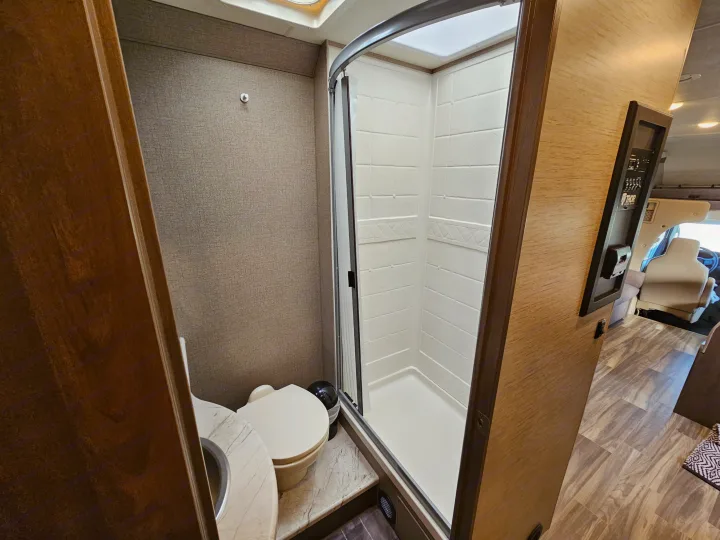 This RV rental features a well-equipped bathroom with a spacious stand-up shower, toilet, and vanity sink.. Thor Motor Coach Freedom Elite 2021
