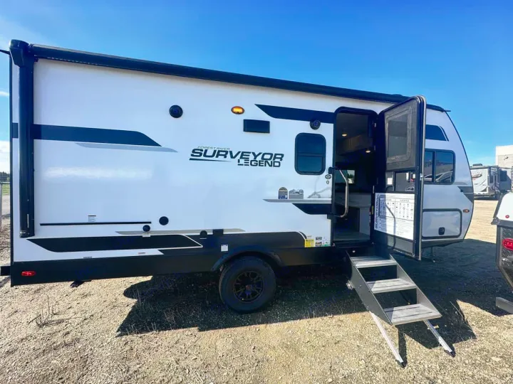 This white Forest River Surveyor Legend RV rental is ready for adventure. Steps lead to its open door.. Forest River Surveyor 19BHLE 2024