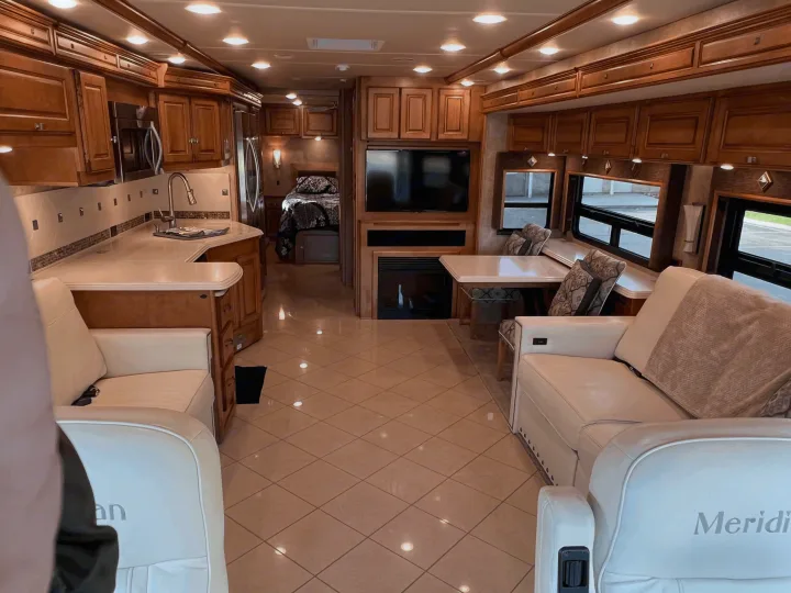 Explore this luxurious RV rental interior, featuring a full kitchen, living space, dining area, and rear bedroom.. Itasca Meridian 2014